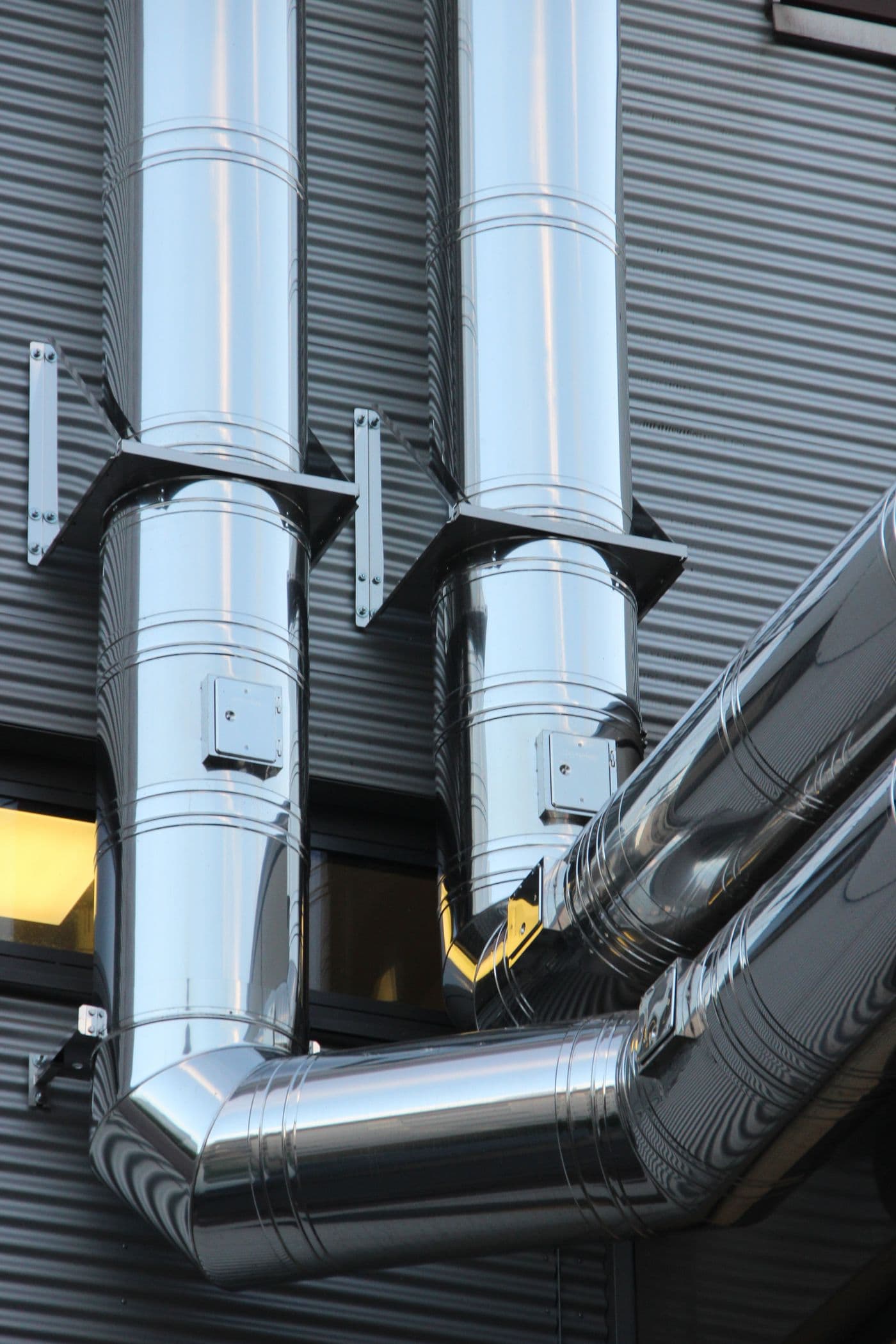 Polished stainless ducting running up the outside of a plant building